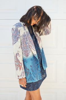 woman wearing a navy blue dress and tapestry blazer