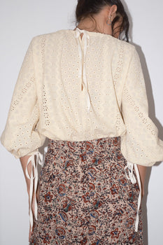 woman wearing eyelet blouse and print skirt back view