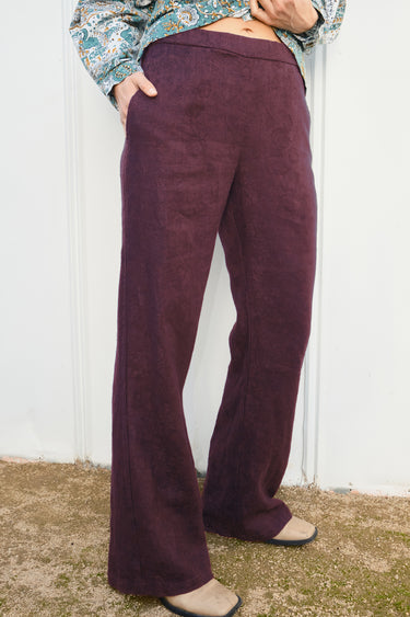 Person wearing black fig flared pants against a white wall.