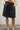 Person wearing black shorts and beige boots against a white wall.