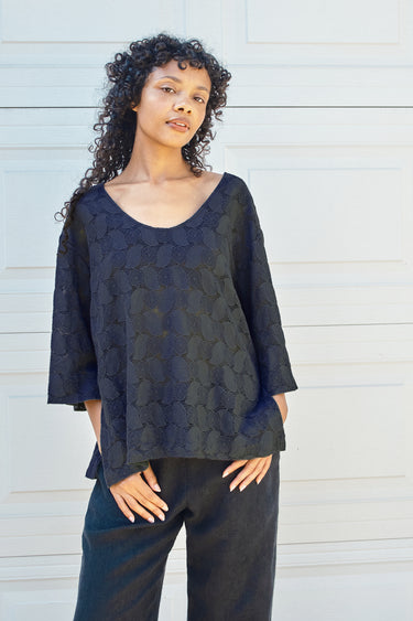 Woman wearing a soft black lace top against a white background