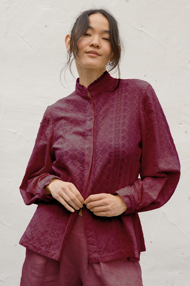 Woman wearing a maroon outfit against a white background