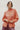 Woman wearing persimmon blouse with lace details against a white background