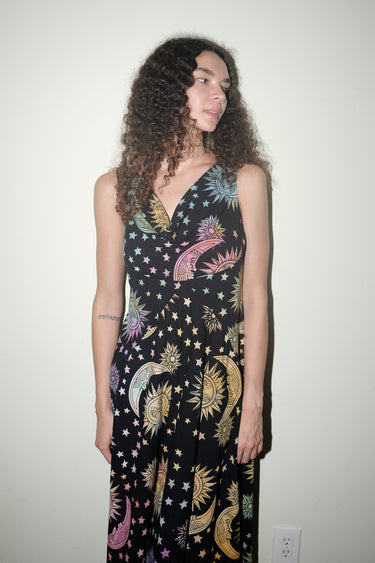 Woman wearing a black dress with colorful celestial pattern against a plain background
