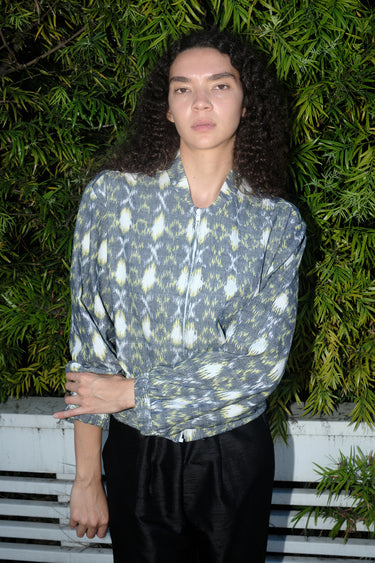 Woman outdoors wearing a gray with white and yellow ikat zip front jacket with black pants.