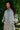 Woman wearing a blue and beige floral patterned outfit standing against a green leafy background