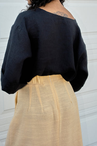 Person wearing a black top and yellow skirt against a white background