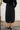 Person wearing a black skirt with a white wall background