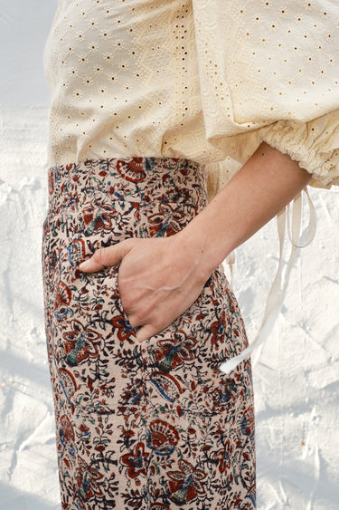 Person wearing a cream blouse with puffed sleeves and patterned skirt.