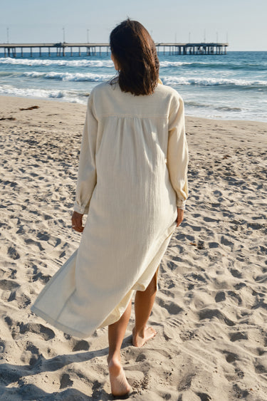 A woman at beach wearing an alabaster midi shirt dress with long sleeves and an obi belt.