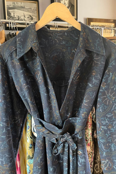 Blue patterned robe on a hanger against a wall with framed pictures.