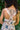 Woman wearing a floral dress with tattoos visible on her back against a natural background