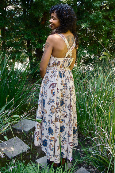 Woman in a floral dress standing in a garden with greenery around
