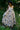 Woman in a floral dress standing in a natural setting with greenery.