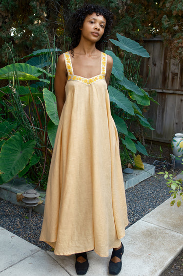 Woman wearing a yellow dress with yellow accents in an outdoor setting
