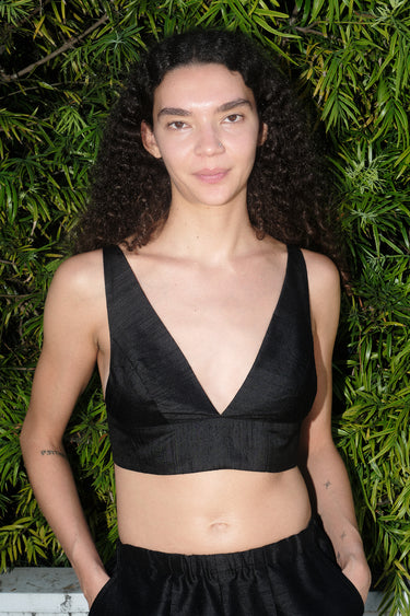 Person wearing a black sleeveless top against a green leafy background
