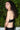 Woman wearing a black bralette against a green leafy background