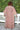 A woman outside standing against greenery wearing a raisin floral tapestry maxi caftan with three quarter balloon sleeves, back view.