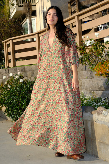 A woman standing outside wearing a beige ground with red and brown floral vintage rose tapestry caftan.