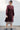 Woman wearing a black fig coat over print skirt with a white background