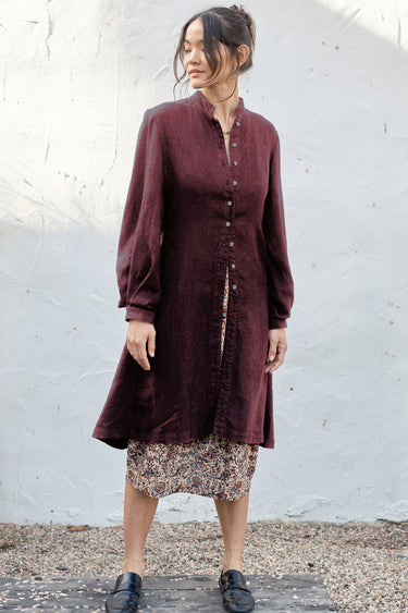 Woman wearing a black fig coat over print skirt with a white background