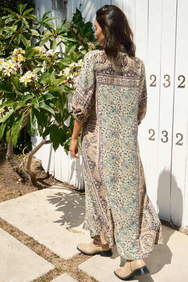 A female model wearing a multicolored floral caftan with three-quarter sleeves. Back view