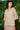 Woman wearing a patterned top and pink skirt against a green leafy background