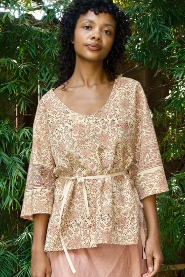 Woman wearing a patterned top with a belt in a natural setting
