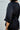 Person wearing a black linen shirt with rolled-up sleeves against a white background