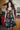A woman standing in a kitchen wearing a knee-length dress in a black ground tapestry with rainbow suns, moons and stars printed on it.