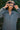 Woman wearing a gray jumpsuit with a blurred green leafy background