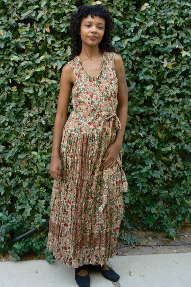 Woman wearing a floral dress standing outdoors with greenery in the background