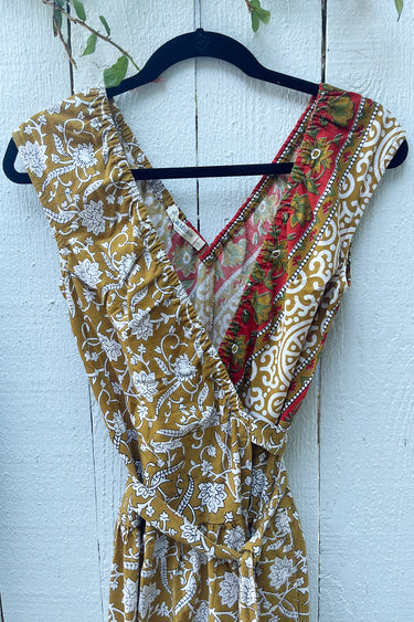 Floral dress with a red and green pattern on a hanger against a white wooden background