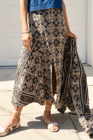 A woman standing in front of a garage door, wearing a midi-length skirt in a geometric tapestry, denim tee top and matching tapestry jacket.
Worn with espadrilles