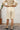 Person wearing a alabaster outfit with shorts and a top, standing against a white wall.
