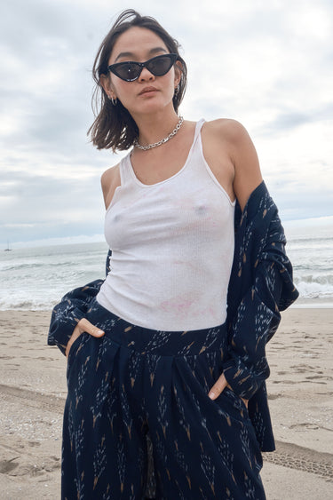 Woman at the beach wearing an ikat low waist trousers, with white tank top and a matching jacket