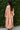 Person wearing a pink outfit standing against a green leafy background