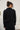 Person wearing a black outfit against a white wall