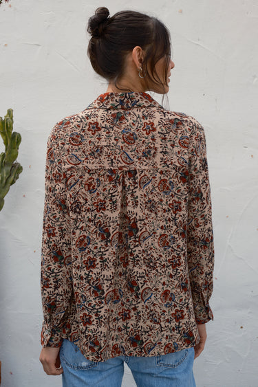 Person wearing a patterned shirt against a white wall