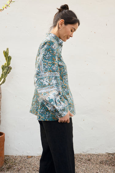 Woman wearing a floral blouse against a white wall