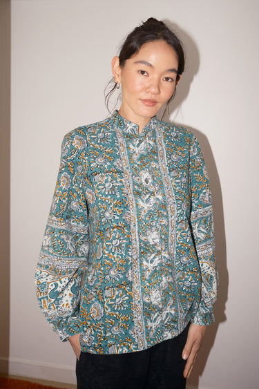 Person wearing a patterned shirt against a plain background
