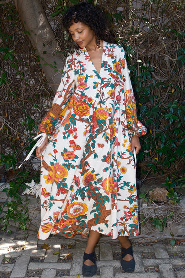 Woman wearing a floral dress standing outdoors with greenery in the background
