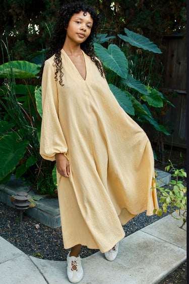 Woman wearing a long mimosa dress standing in a garden setting