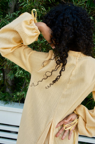 Person wearing a bmimosa long-sleeve dress with a blurred green outdoor background