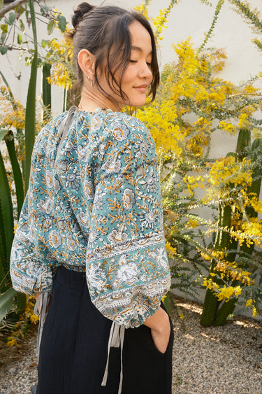 Woman wearing a floral blouse standing among yellow flowers