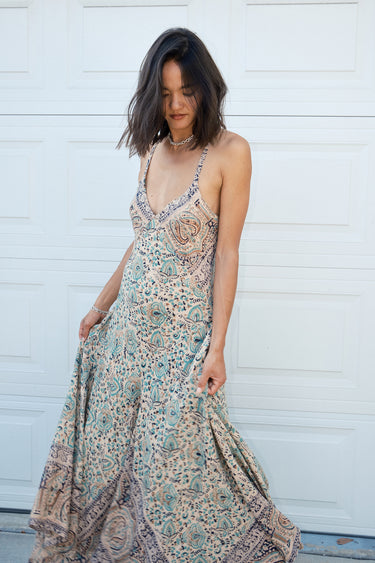 A woman standing in front of a white garage door, wearing a multicolored floral Nova slip dress .