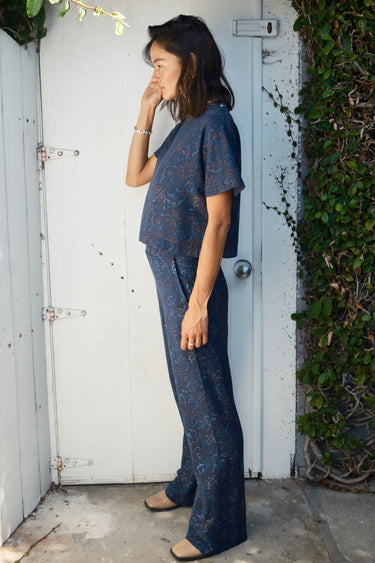 A person wearing a navy blue flare legged full length pant with a mid rise and hand woven, hand block printed Indian Tapestry.