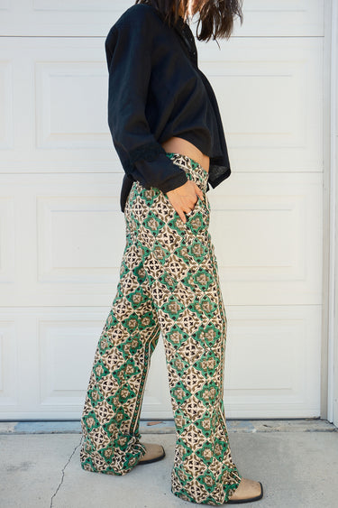A person wearing a flare legged full length pant with a mid rise and a hand block printed Indian Tapestry design.