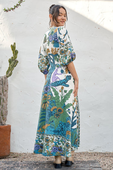 A woman modeling a maxi dress with a tree of life print, featuring voluminous 3/4 sleeves and a V-neckline.