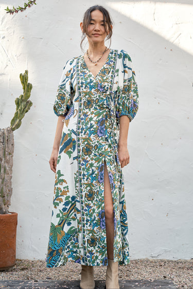 A woman modeling a maxi dress with a tree of life print, featuring voluminous 3/4 sleeves and a V-neckline.